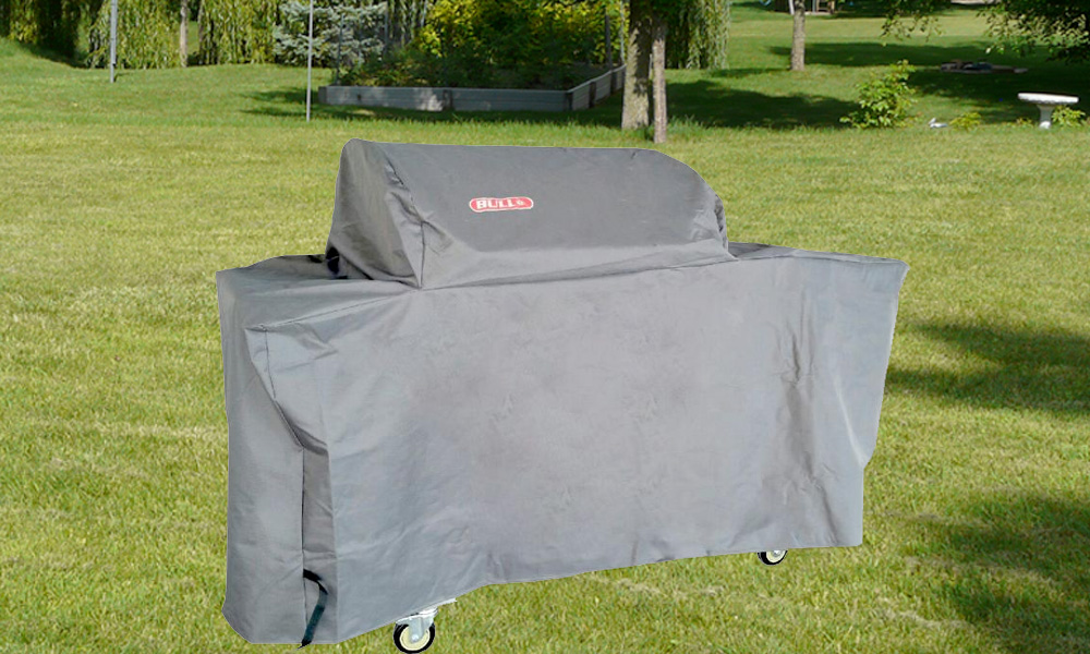 bull bbq grill cart covered with a grey bull grill cover outside with a green grass field background