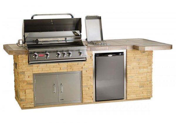 Stainless steel bull bbq grill island on a rock tile counter with storage compartments, drawers, water faucet, side burner, and a refrigerator