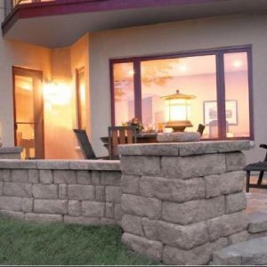 Natural stone patio and wall constructed in backyard in Pineville, North Carolina