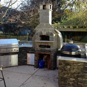 Outdoor kitchen with fireplace and built-in grill on patio in Pineville, North Carolina