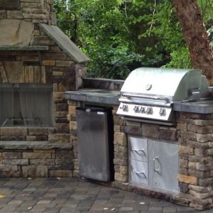 Stone kitchen island next to fireplace outside in Pineville, North Carolina