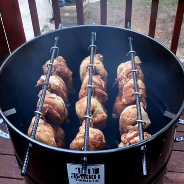 Close-up of a black painted metal 18.5 IN Classic Pit Barrel cooker cooking twelve chickens on hooks