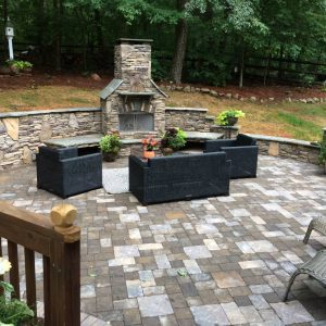 fireplace on paved patio surrounded by patio furniture in backyard
