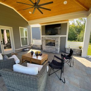 Paved patio with outdoor fireplace, patio furniture, and hanging tv in backyard of north carolina home