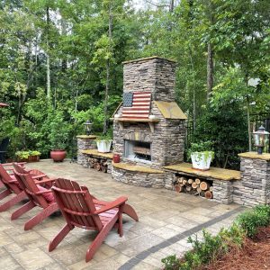 Stone outdoor fireplace on tiled patio with patio furniture and american flag