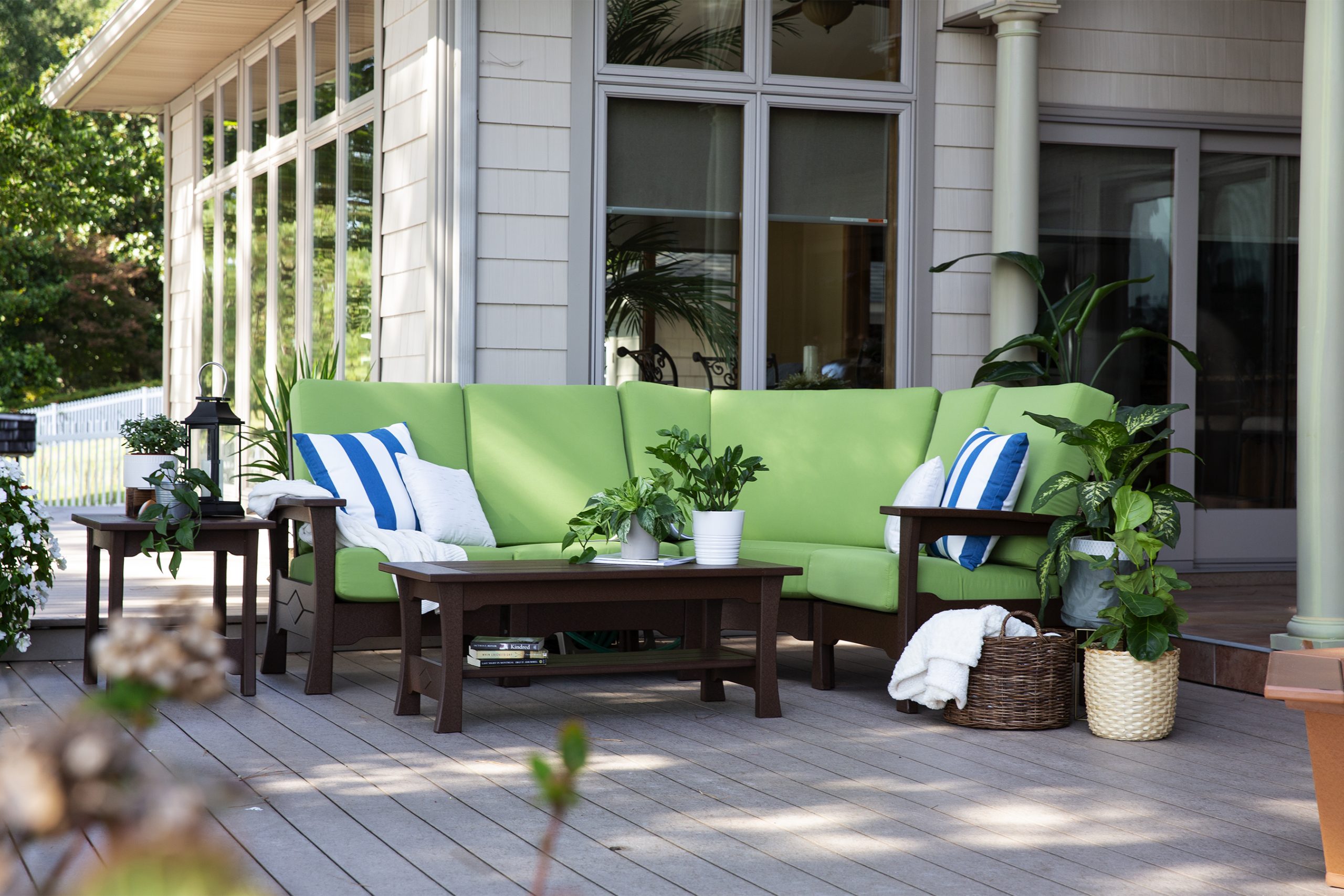 Green Outdoor sectional with striped pillows and table on deck next to house