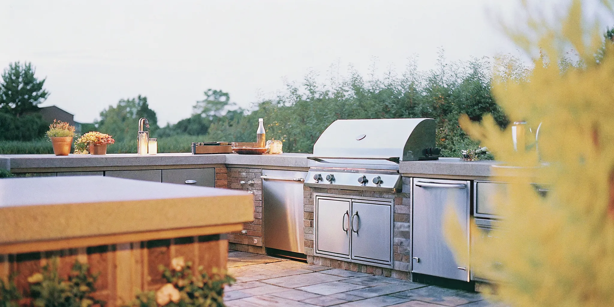 Outdoor kitchen with a premium built-in gas grill, stainless steel construction, warm evening lighting in a Carolina backyard